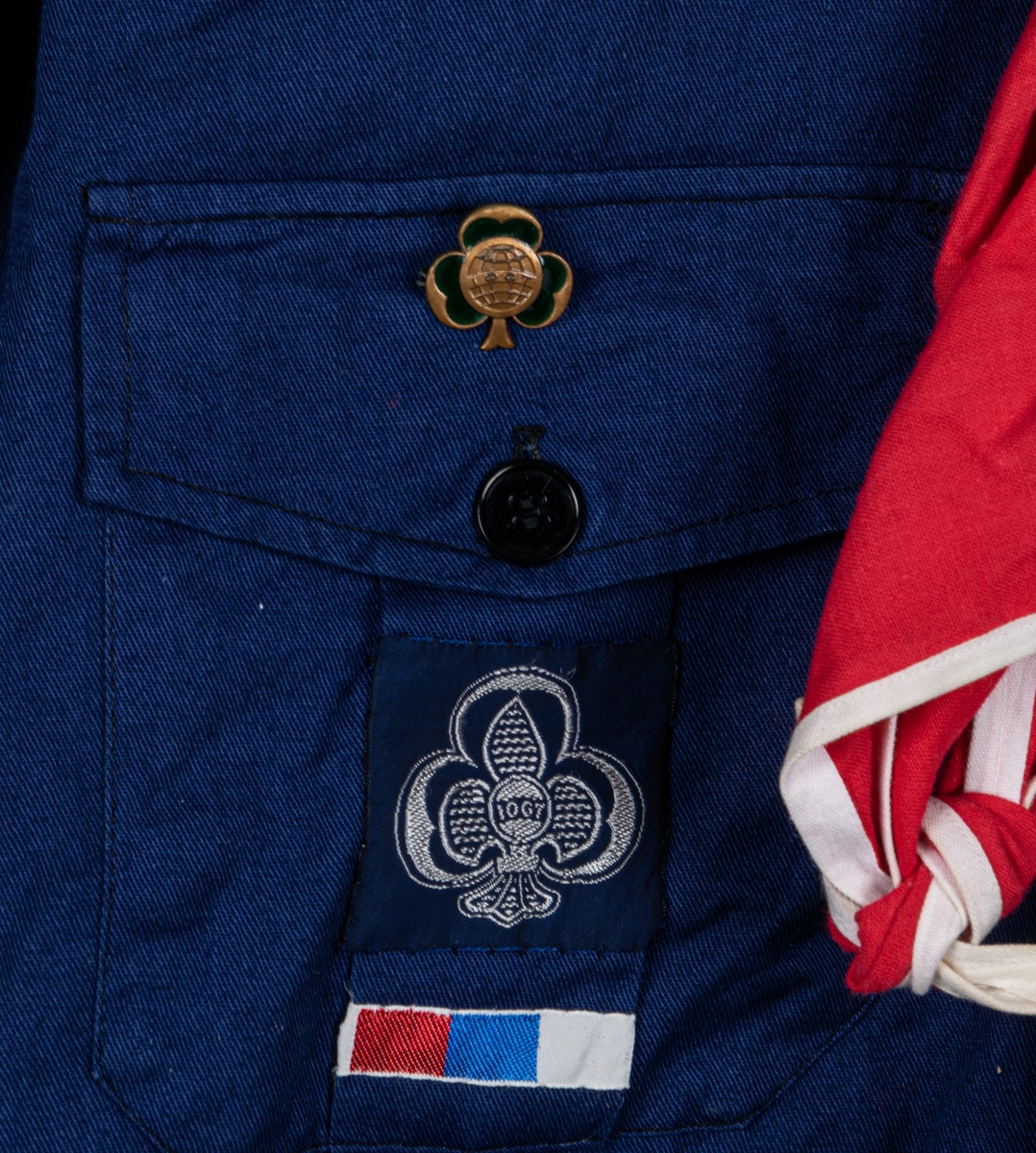 Blå scoutskjorta av bomull. Knäppning på bröstet samt fickor med IOGT-pin på den vänstra. Tygmärke på ena fickan. På höger axel tygmärke: "Bomhus", på vänster axel märke med brinnande fackla och texten "Var redo", och "Seniorscout". Runt nacken en röd sjal med vit kant samt en blåvit snodd med svart visselpipa.

I nacken vävd etikett: "Specialtillverkad för AB SCOUTKÖP, IOGT:s scoutförbund".
Storlek 38.