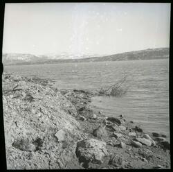 Fotografi av en fjære ved Lundfjorden med sand og steiner og