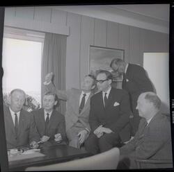 Fotografi av fem menn kledd i dresser med slips som sitter p