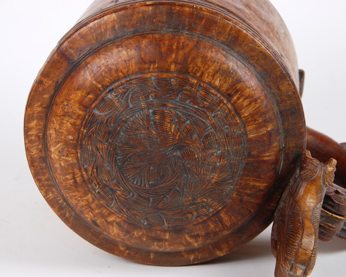 Kanne av dreid valbjørk. Lokk med akantusskurd. Løveformet lokkåpner. Hank med bladranke. Tre løveføtter.