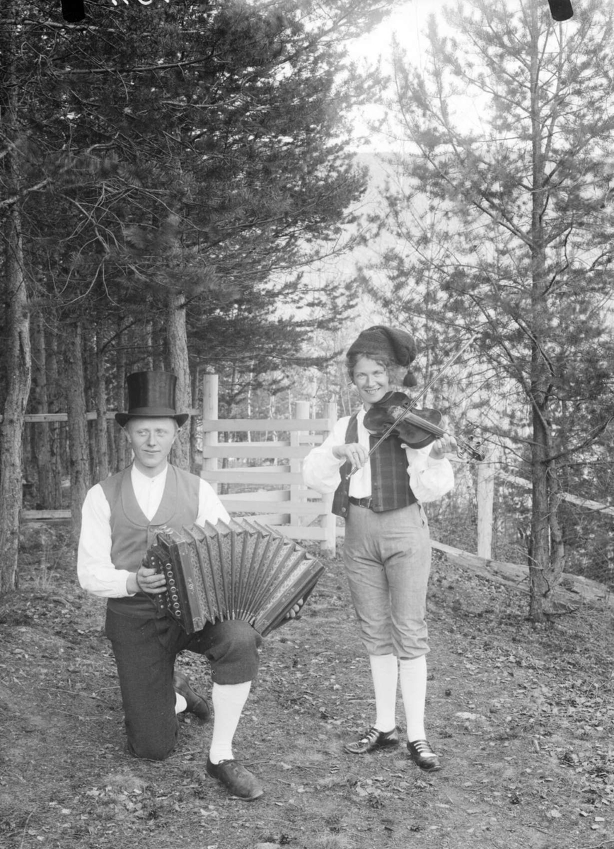 30.04.1908. Arild Furuheim og Frk. Giverholdt. Gruppebilde, mann med trekkspill og flosshatt, kvinne med fele.