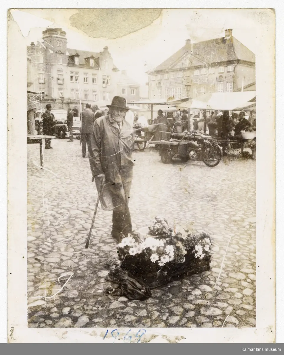 Gunnar Edvin Franzén säljer blommor på Stortorget i Kalmar 1969. Påskrift baksida: Blomsterhandel på Kalmar torg Gunnar Edvin Franzén 1969.