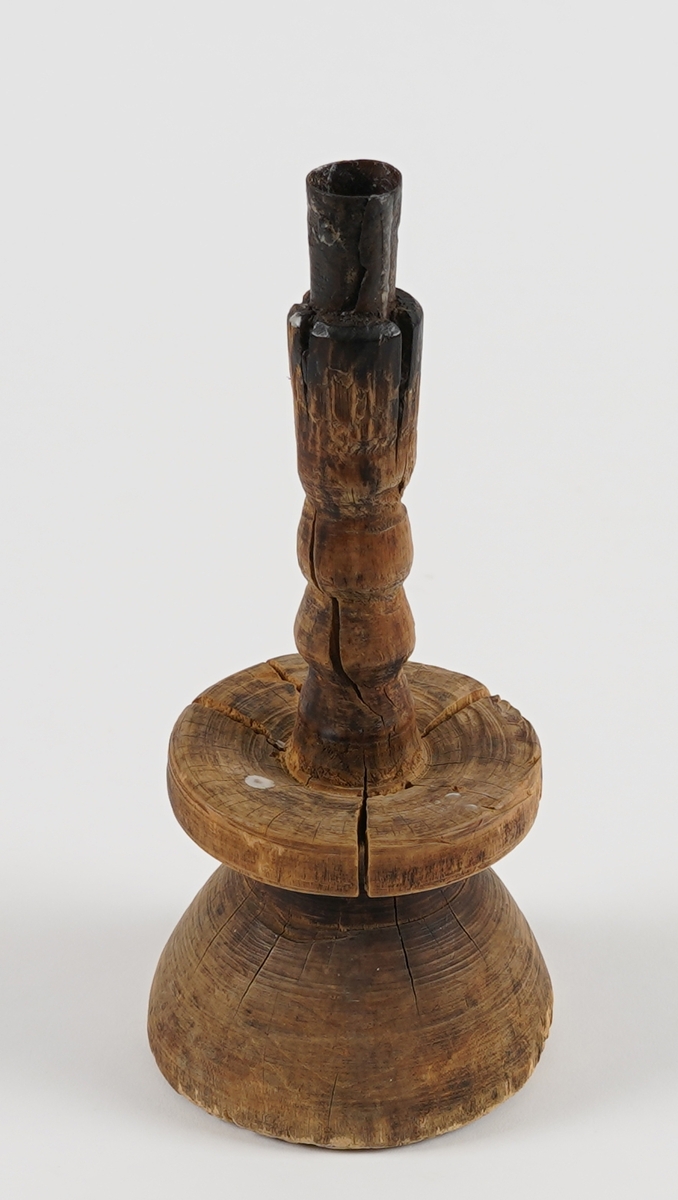 Form: Lysestake av tre med jarnpipe. Massingfasong med massiv "kvelva" fot og brei skål.
