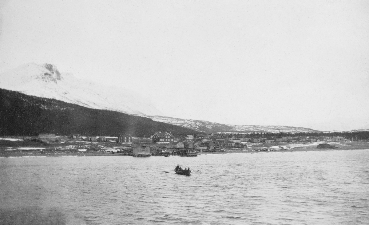 Markedsplassen i Skibotn i Troms, fotografert fra dekket på et fartøy på Skibotnbukta, antakelig en vårdag omkring 1. verdenskrig.  På sjøflata ses en robåt med to årepar.  På bakken mot sjøen ligger en del våningshus med nedenforliggende båthus.  Bak disse igjen, til venstre på bildet, en skogkledd åsrygg.  I bakgrunnen en snødekt fjellrygg. 

Skibotn er i dag kommunesenter i Storfjord ved Lyngenfjorden. Dette tettstedet har lange tradisjoner som markedsplass - se fanen «Opplysninger».