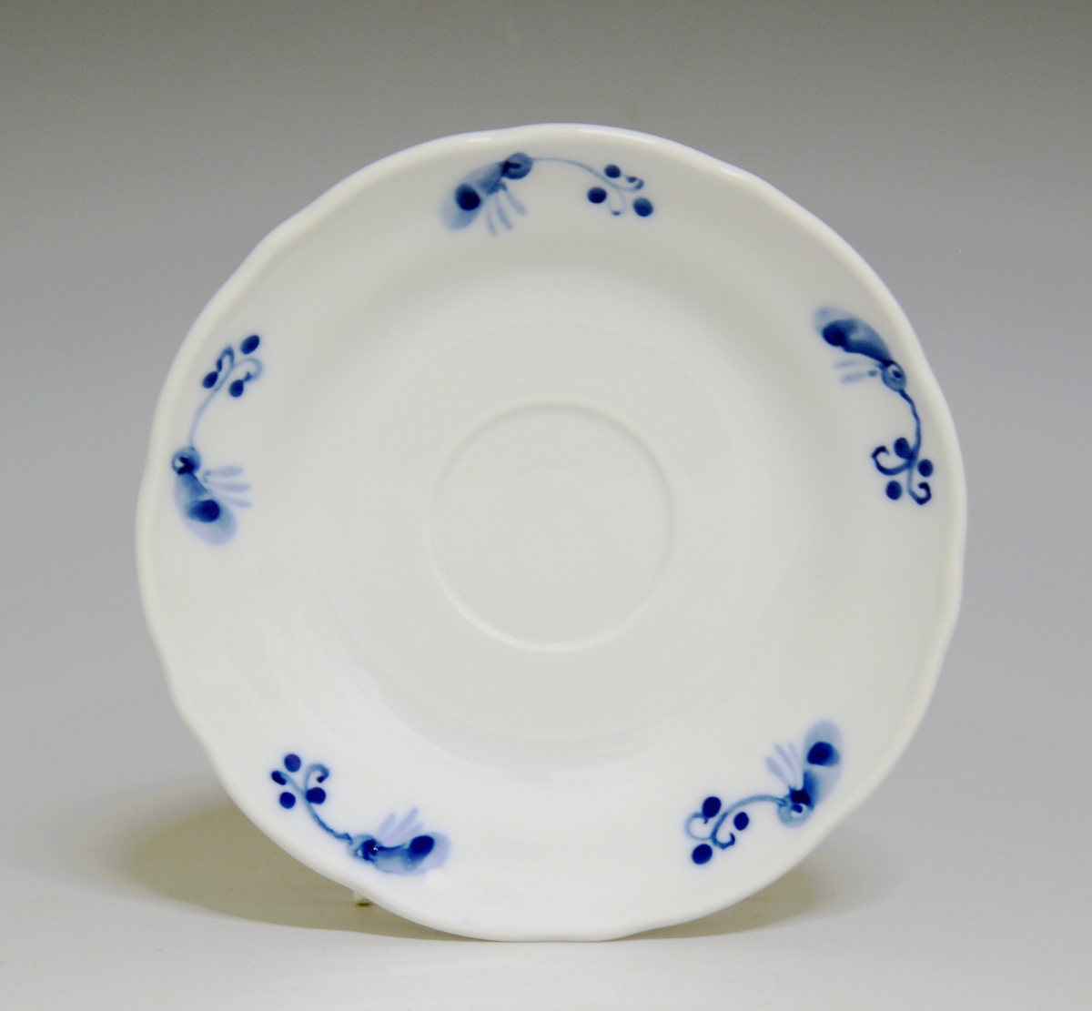 Kaffeskål av porselen. Hvit glasur. Håndmalt blå underglasurdekor i fem felter på fanen.
Modell: Victoria, 1800
Uten fabrikkmerke.