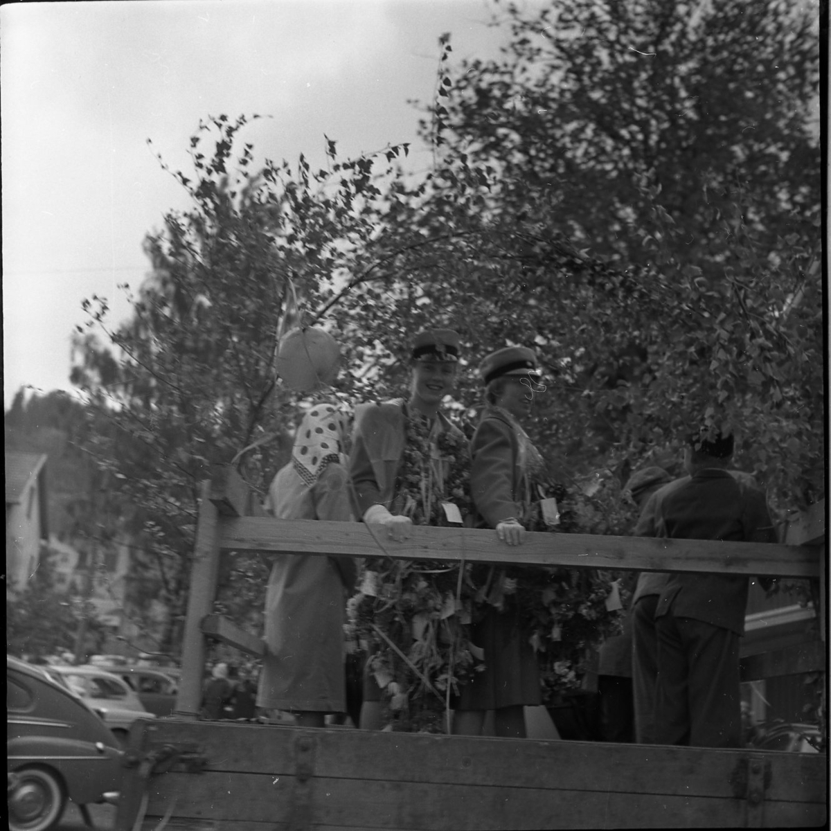 Realexamen 1961. Bilden föreställer ett lstbilsflak. Flaket är klädd med björkris och ballonger. På flaket står glada studenter.