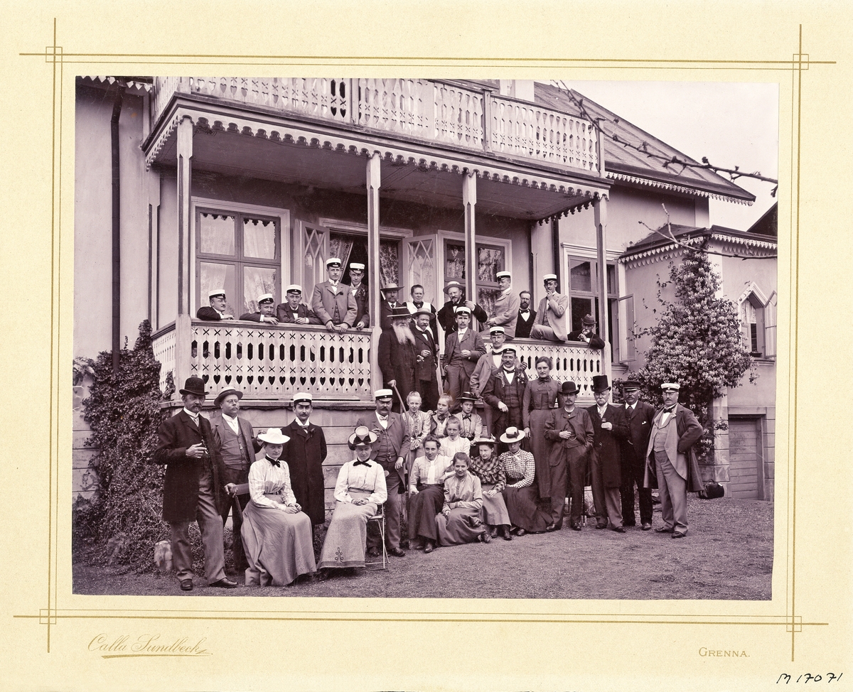 Ett sällskap, troligen diverse sommargäster, poserar för fotografen vid en veranda i Gränna.
