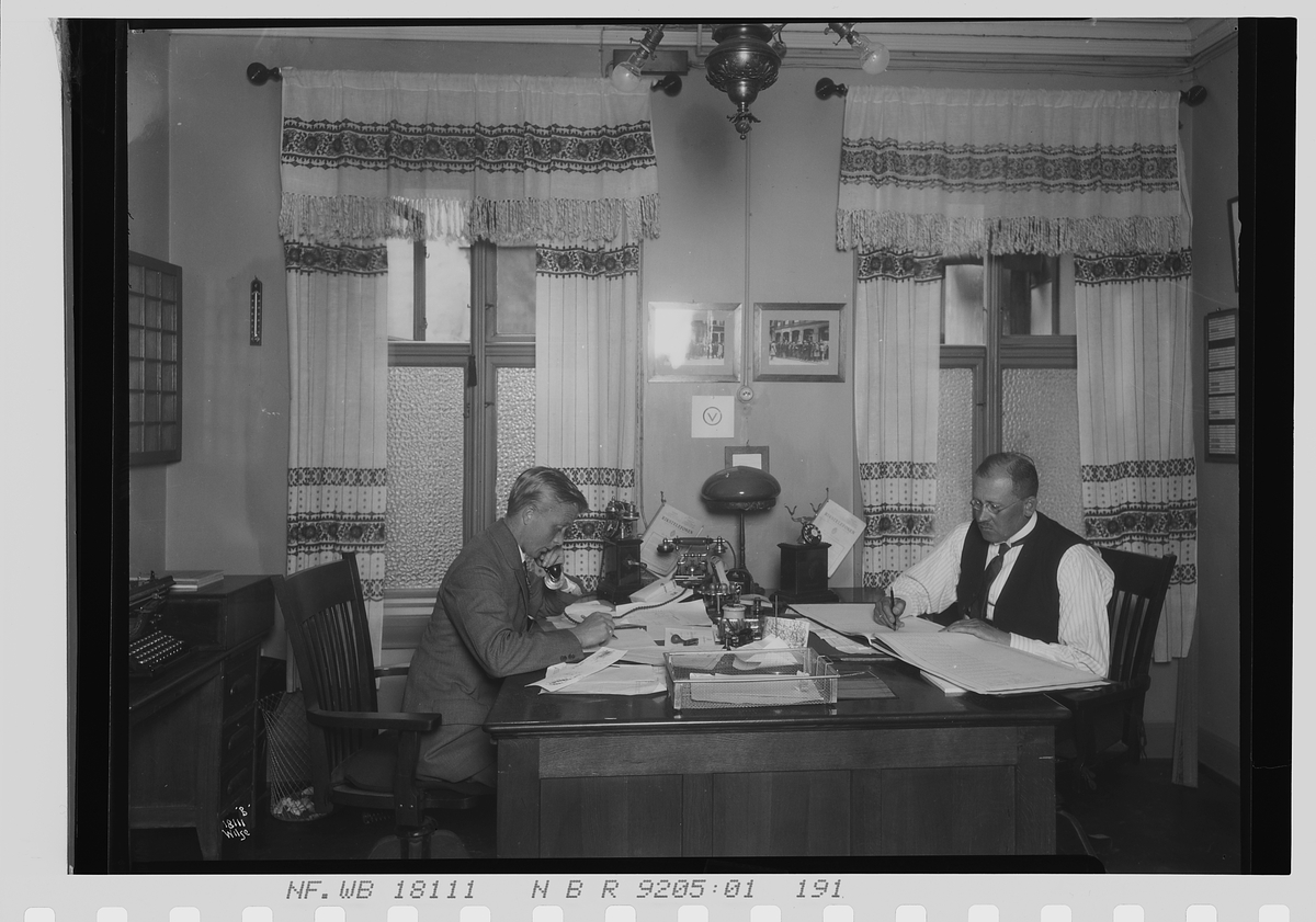 To menn sitter på felles kontor, Vinmonopolet. Fotografert 1924.