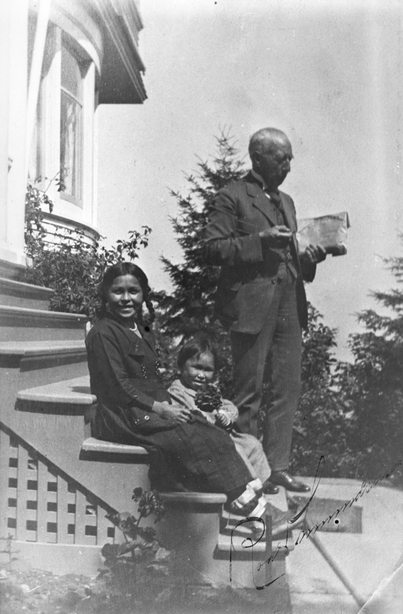 Roaldf Amundsen på trappen sammen med to eskimoer, mor og datter. Fotografert 1926.