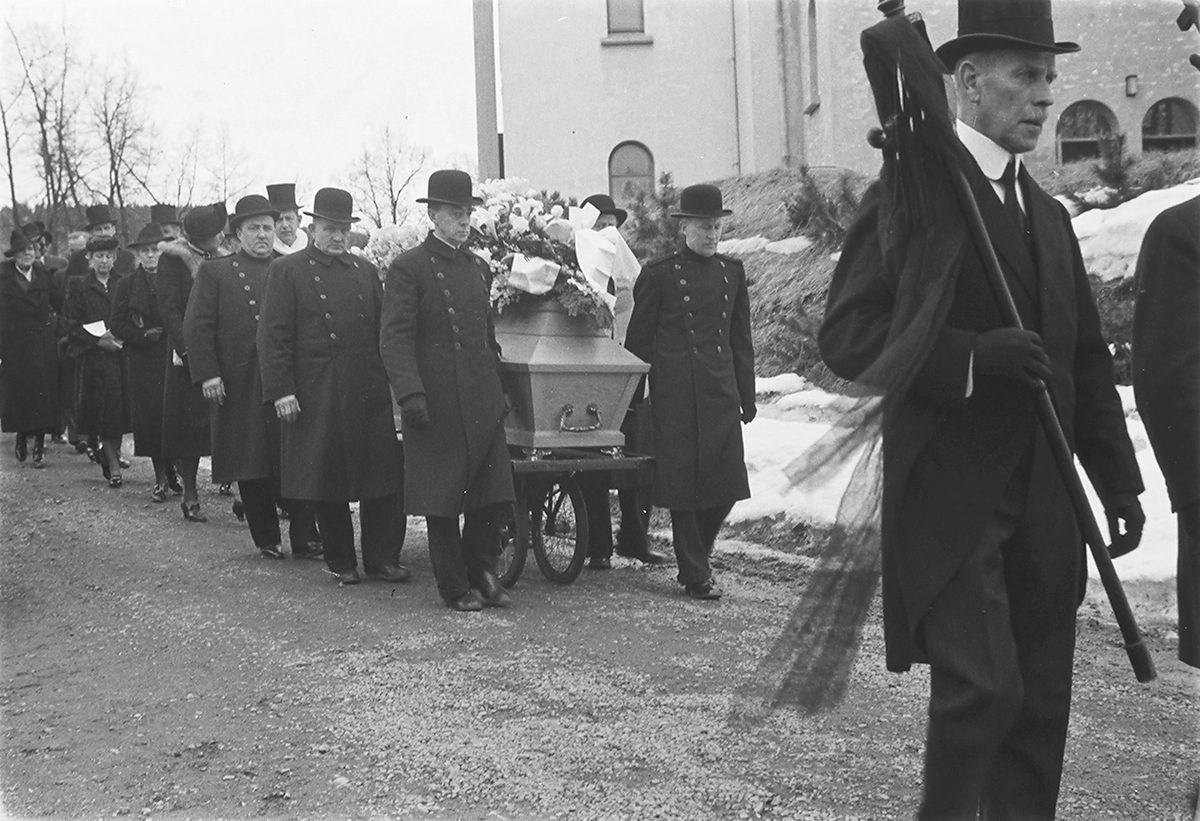 Begravelsesfølge til fru Kiær utenfor Ullern kirke ledet av to menn med "faner". Fotografert 1940.