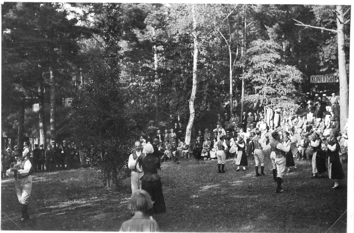 Folkdans på Grännaberget. Publik sitter i slänten i bakgrunden.