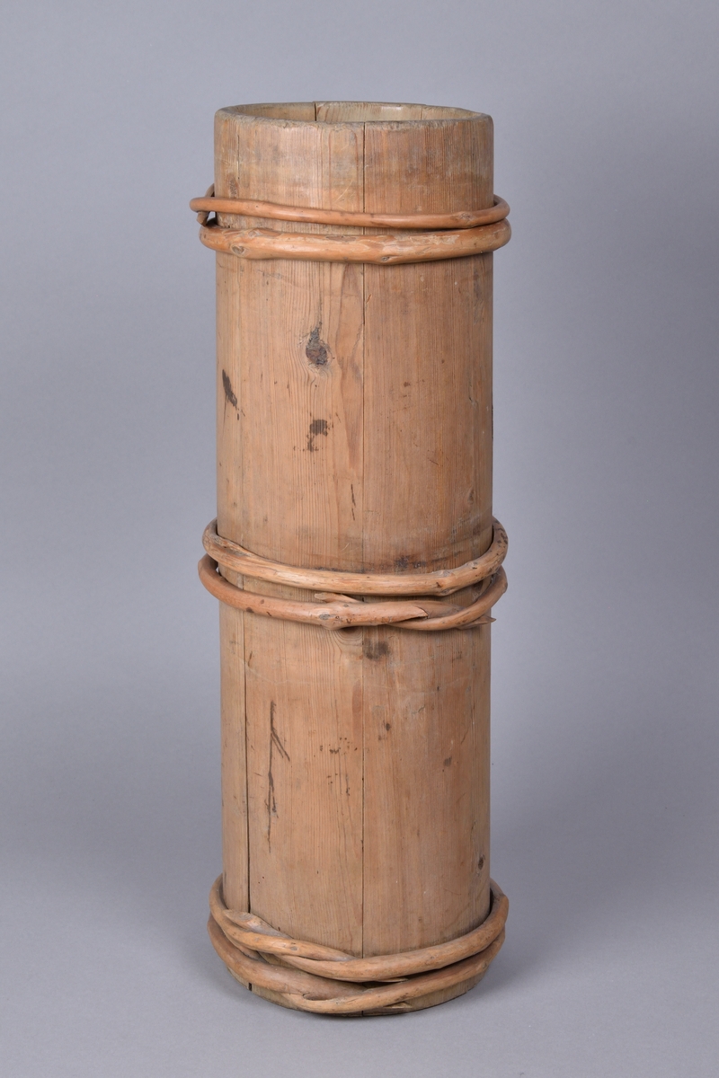 Smörkärna tillverkad i furu och en, laggad. Cylinderformad med åtta band av vidjor. Med lock, samt stöt med rundat skaft och korsformad botten.  