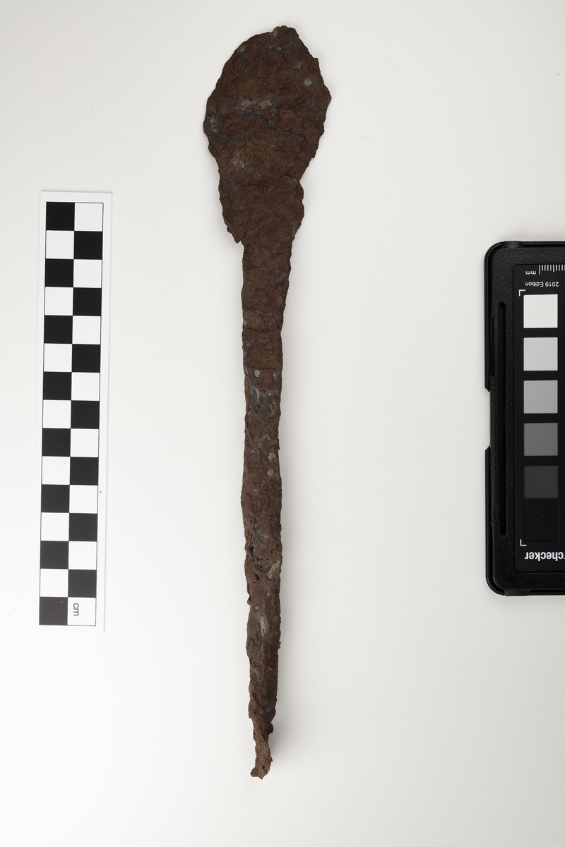 Barre av jern av typen R. 438. Lengde 27 cm, st.b. 4,4 cm. minste b. 1,0 cm. Vekt 105 g. 