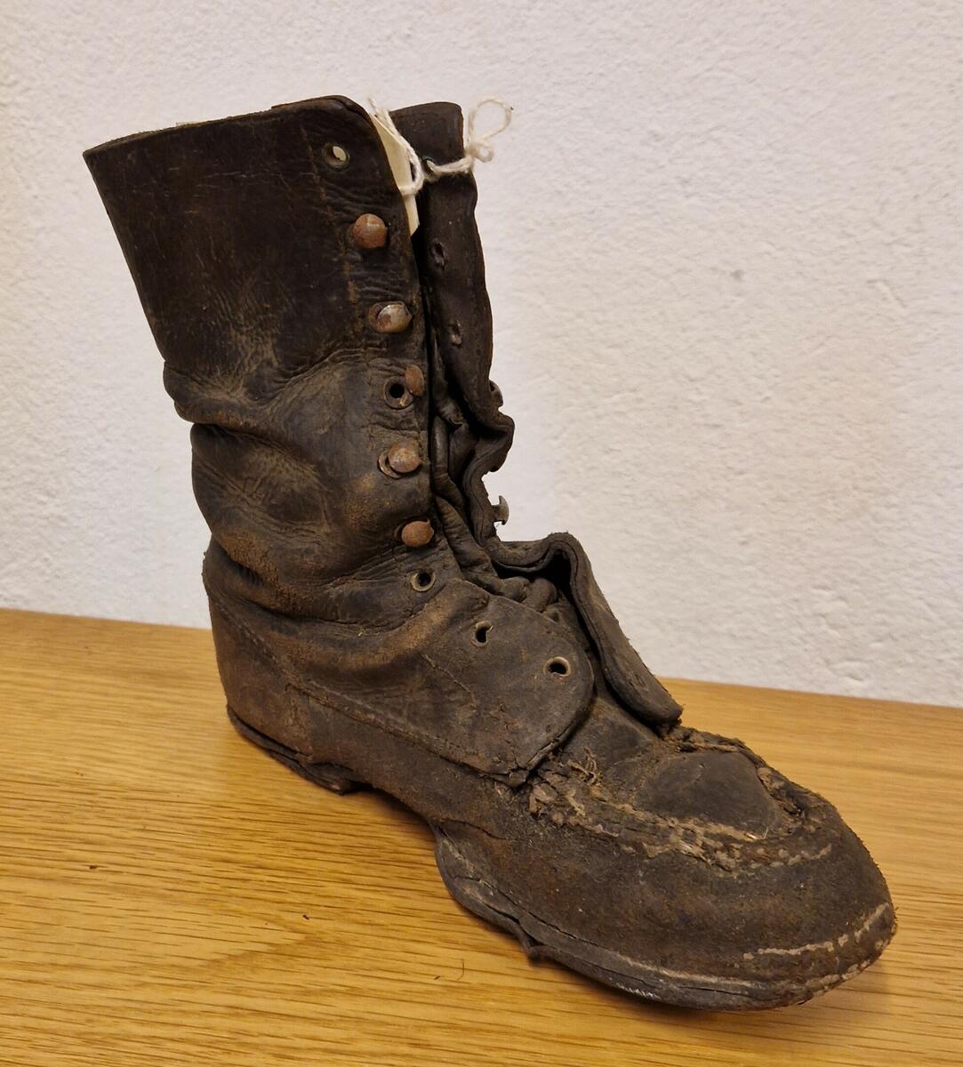 Barnsko, läder, typ näbbkänga,  med 10 st höljor av metall, pluggade sulor. Gåva av Ingvar Wiklund, Sundsvall.