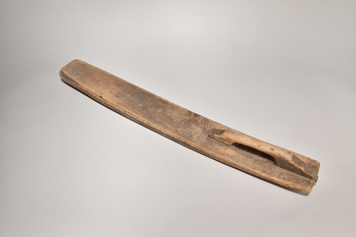 Kaveldon tillverkat i trä, med platt bräde samt handtag. Ovansidan med inskriften: "ANAO 1725 DEN 3 OCTOBER". 