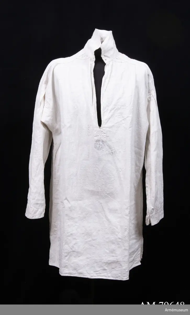 Skjorta av grov vit linnelärft med tre stämplar framtill: ”?813” (otydlig), ”År 1856” och ”Krigssjukvårdsförrådet T4”. Skjortan har långa ärmar med litet sprund nertill, ok på axlarna, hög ståndkrage med sydda snörhål för snodd i varje sida, djupt halssprund med träns, och slits i sidsömmarna nertill. Den är helt handsydd.
Tyget är handvävt i 640 mm bredd - stadkant syns i båda slitsarna nertill.

Troligen är plagget en skjorta m/1845, nattskjorta eller sjukhuströja. Jämför t ex AM.013574.