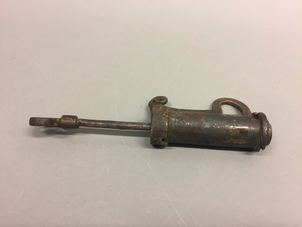 Sylinderforma lås med nøkkel. Nøkkelen skruvast inni låsen og har gjenger i den eine enden. Låsen er intakt.