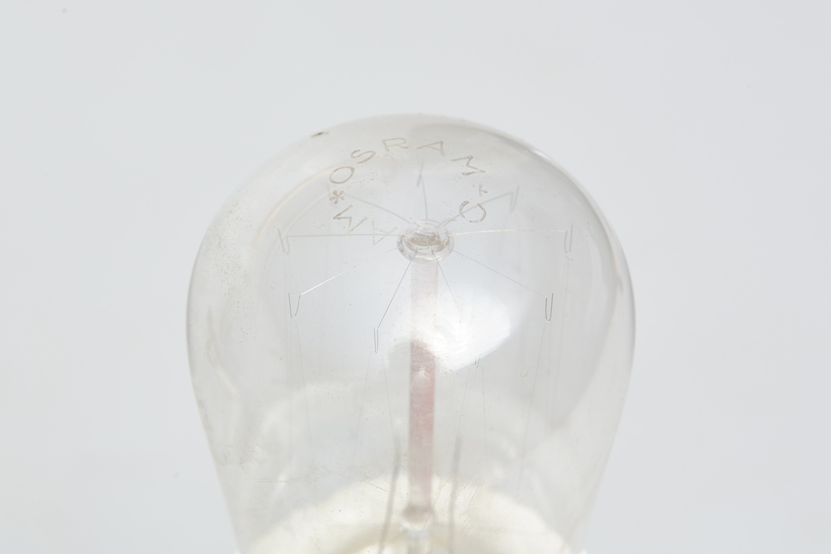 Heisbar parafinlampe ombygd for elektrisitet. Fra Høgbakken. Enkelstående med kuppel bunn i hvit porselen.  Det stikker ut ett tau ut av midten.