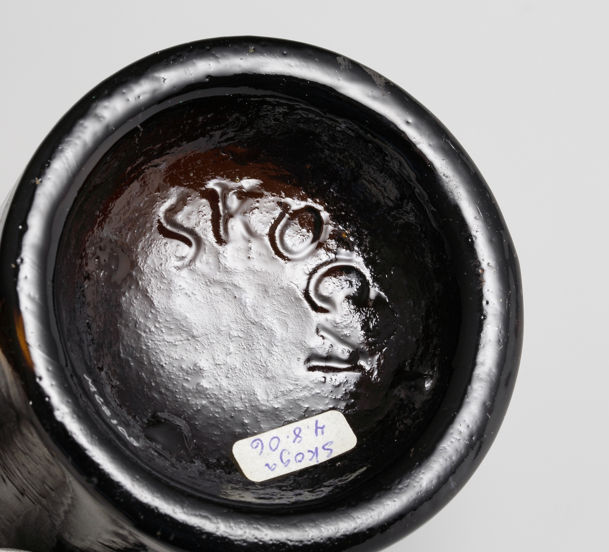 Brun flaskbotten av engelsk modell, tillverkad i tredelad järnform på Skoga glasbruk.