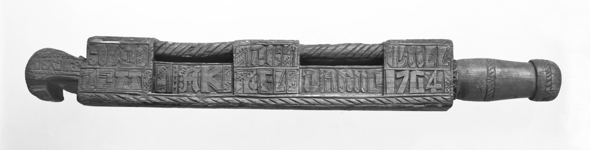 Mangletre
Mangletre, av omtrent kvadratisk gjennemsnitt, utskåret og bedekket med islandske innskrifter, datert 1764. Bakre ende har rundt skaft, kroket snute. 52 cm. Langt
Tre