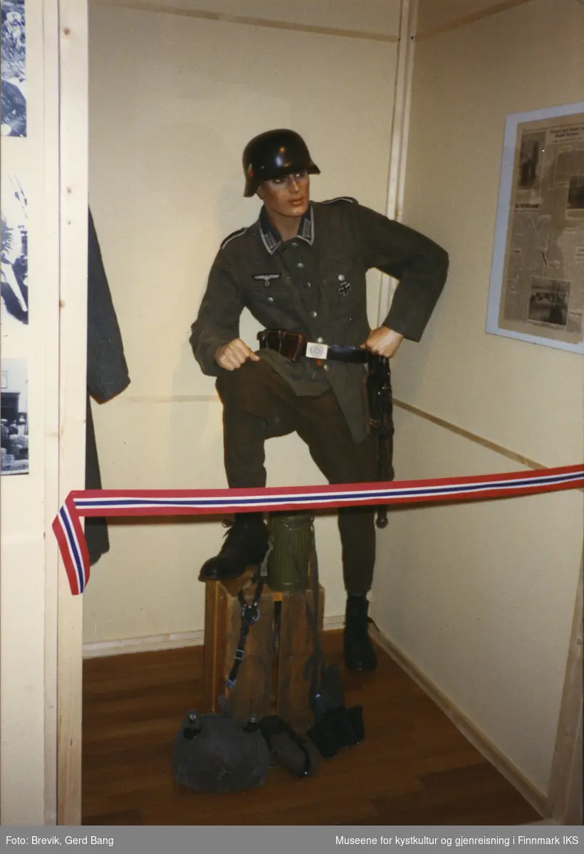 Bildet viser en del av Frigjøringsutstillingen i bystyresalen i Hammerfest som ble vist frem fra 6. juni til 10. august i 1995.
I utstillingen var det iscenesatt noen mindre rom med gjenstander og utstillingsdukker, slik denne som fremstiller en tysk soldat med uniform.