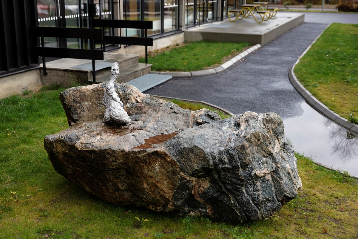 Skulpturen "Varde" er et møte mellom en stein og en kvinneskikkelse utført i metall. Skikkelsen og steinen speiler hverandre gjennom tegninger i steinen. Skikkelsen ser ut som hun snur seg mot eller fra noe: er hun på vakt eller har hun oppdaget noe uventet? Ordet varde er beslektet med å være var, synonymt med å være oppmerksom, varsom, sky eller følsom. En varde kjenner vi som oppstablede steiner som ofte er plassert på fjelltopper og stier som grense – eller veimerker. De er et tegn på at du er på riktig vei.
