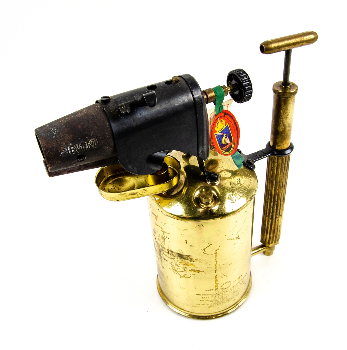 Blåslampa Max Sievert Typ 263, tillverkat i mässing och annan metall. Föremålet består av en 2 liters bensinbehållare i guld mässing, en handpump, och en vindskydd i svart metall. I föremålet finns det bruksanvisning till blåslampan.