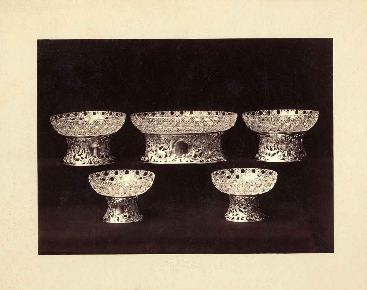 Ett antal skålar med slipad dekor, på ornerade och genombrutna metallfötter. Kosta 1900.