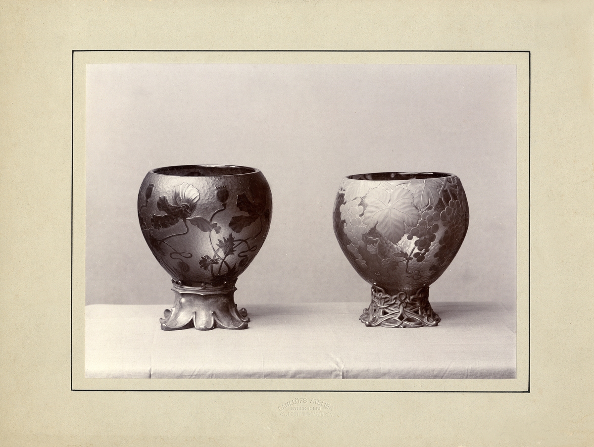 Två vaser med överfångsdekor på ornerade och genombrutna metallfötter. Kosta ca 1900.
