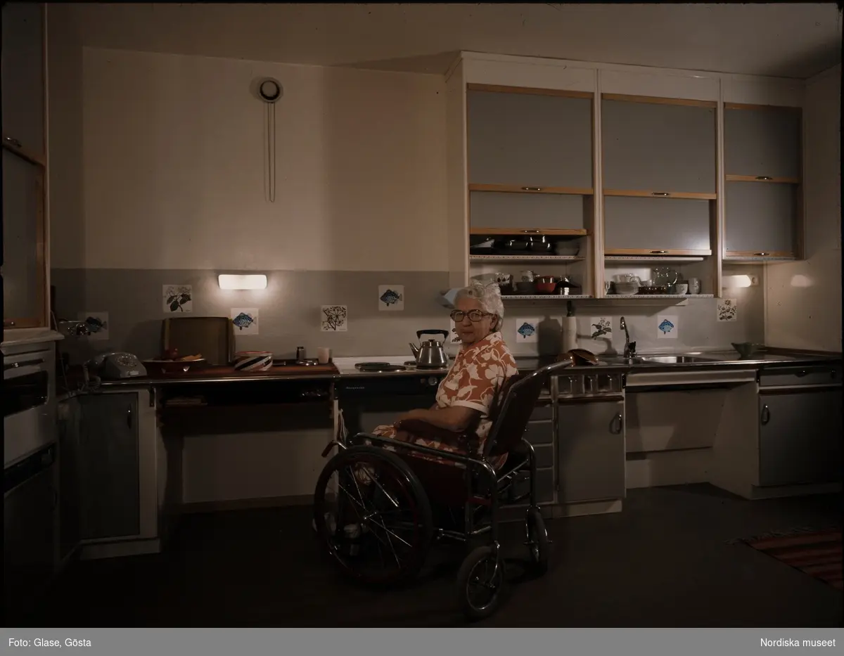 Orminge. En äldre kvinna i rullstol i ett kök.