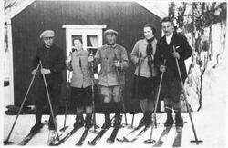 Gruppebilde av folk på skitur, fotografert utenfor hytte ved