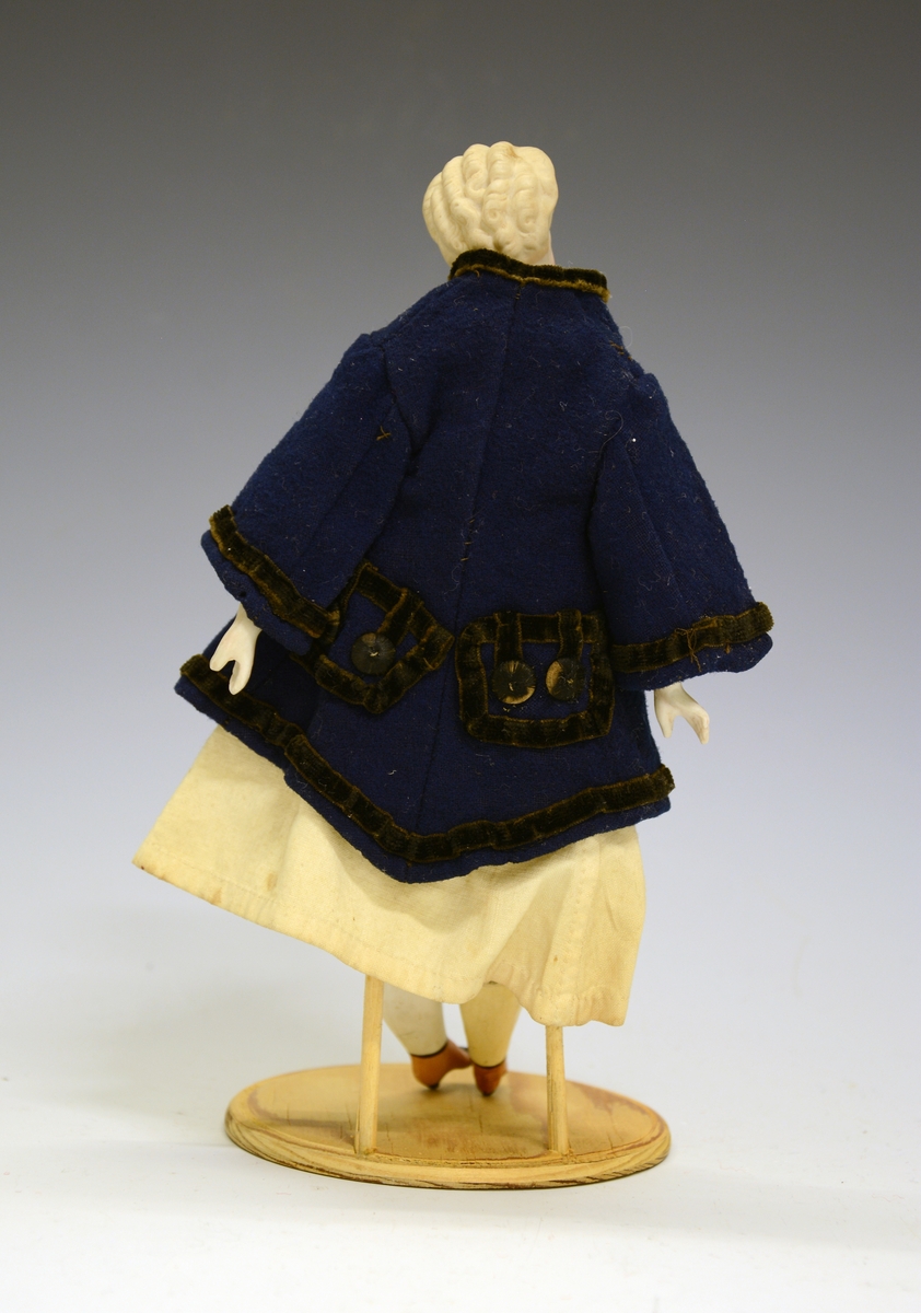 Fra protokollen: Porcelenshovud, med blåsvart kanta jakke og kvit kjole. Har fått ett nytt bein etter innkomsten ved museet. (R. Berge).