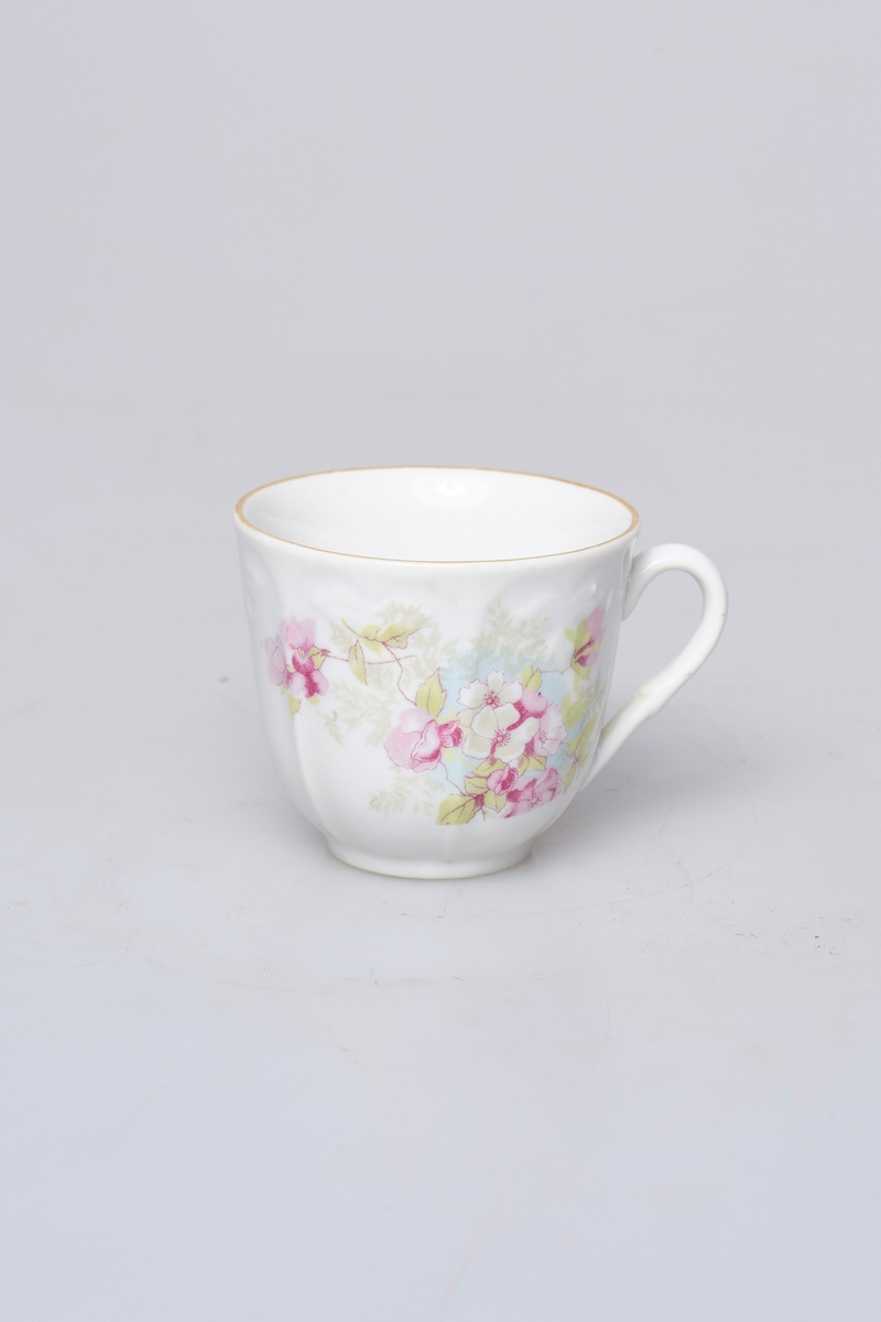 Kaffekopp (b) og skål (a). Hvit med rosa, grønt og lyseblå dekor. Den har gullkant og et rosemotiv på hver side. Skålen har mønstret gullkant og to rosemotiv.