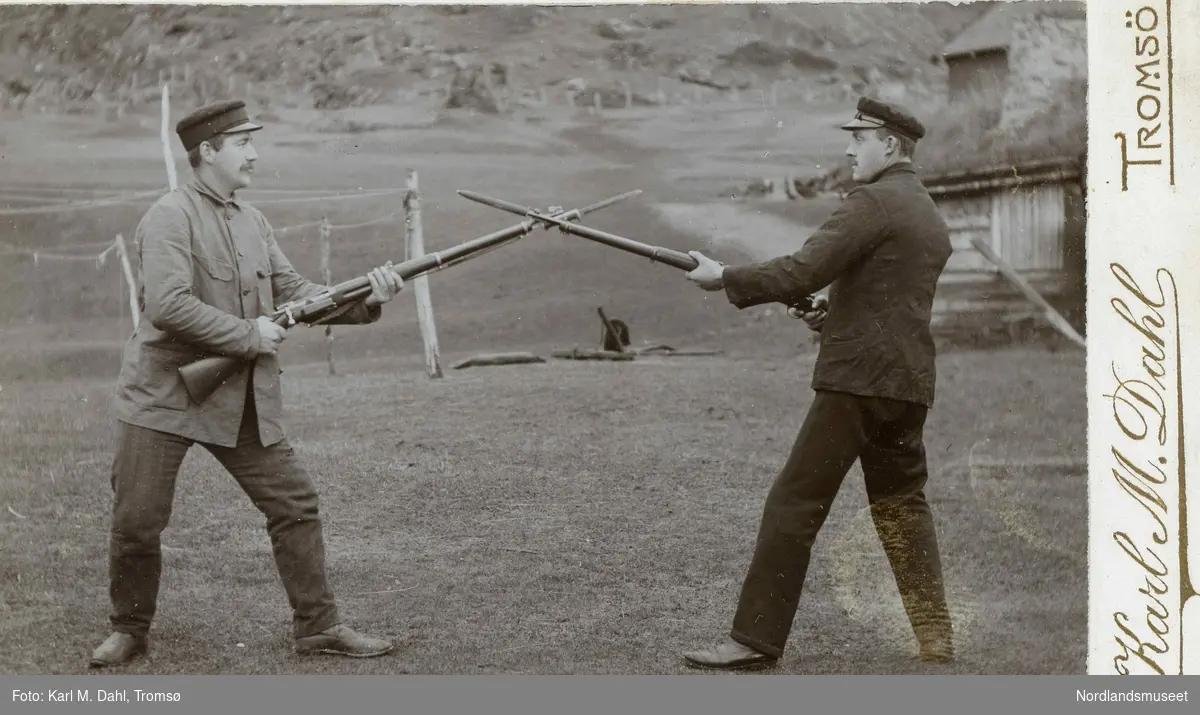 To menn i uniform som står oppstilt mot hverandre med geværer med bajonett.