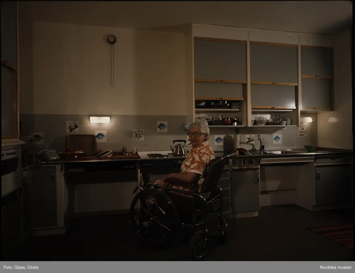 Orminge. Handikapp. En äldre kvinna i rullstol i ett kök.