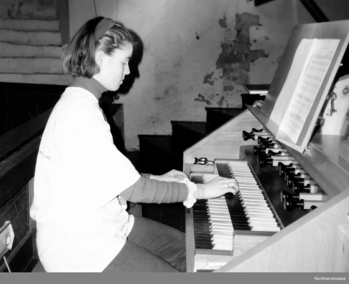 Jente spiller orgel. Bildet er fra avisa Tidens Krav sitt arkiv i tidsrommet 1970-1994. Nå i Nordmøre museums fotosamling.