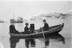 Tre menn i en robåt i Kilbotn. Den ene holder en sveivegramm