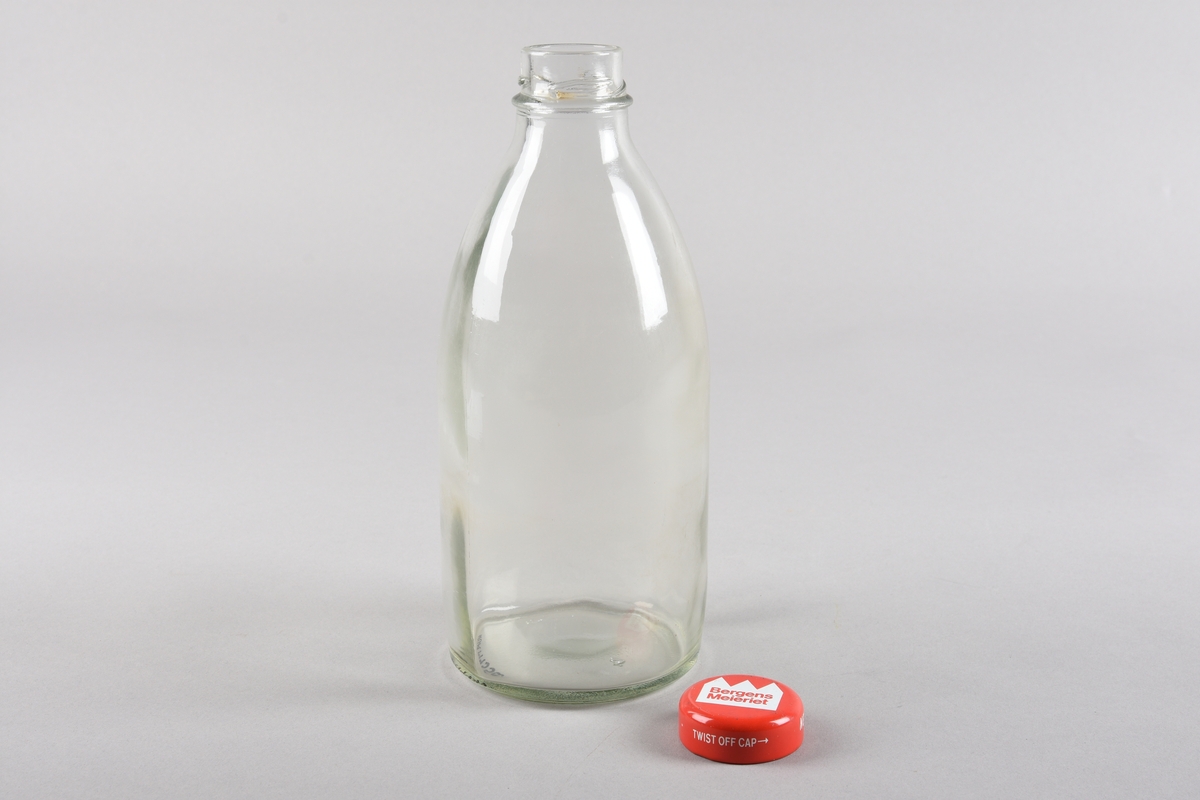 Mjølke-/saftflaske i støypt glas. Flaska har sylindrisk korpus og er runda inn mot tut med gjengar for skrukork. Korken er i lakka metall med plastbelegg på innsida, flat topp med runda kant som går ned over flasketuten. Tekst trykt på.