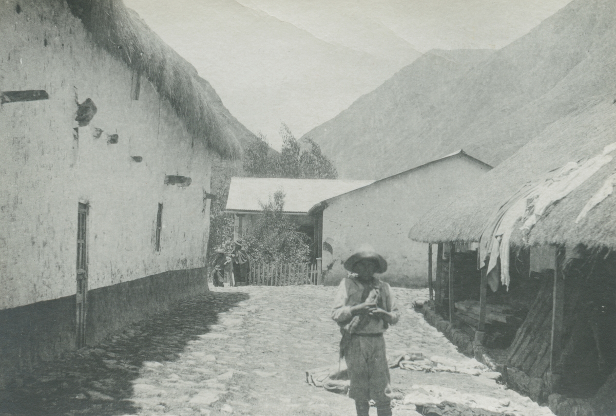 Fotografi från expedition till Peru 1920. Motiv av en pojke som står på en liten gata i en bergsby.