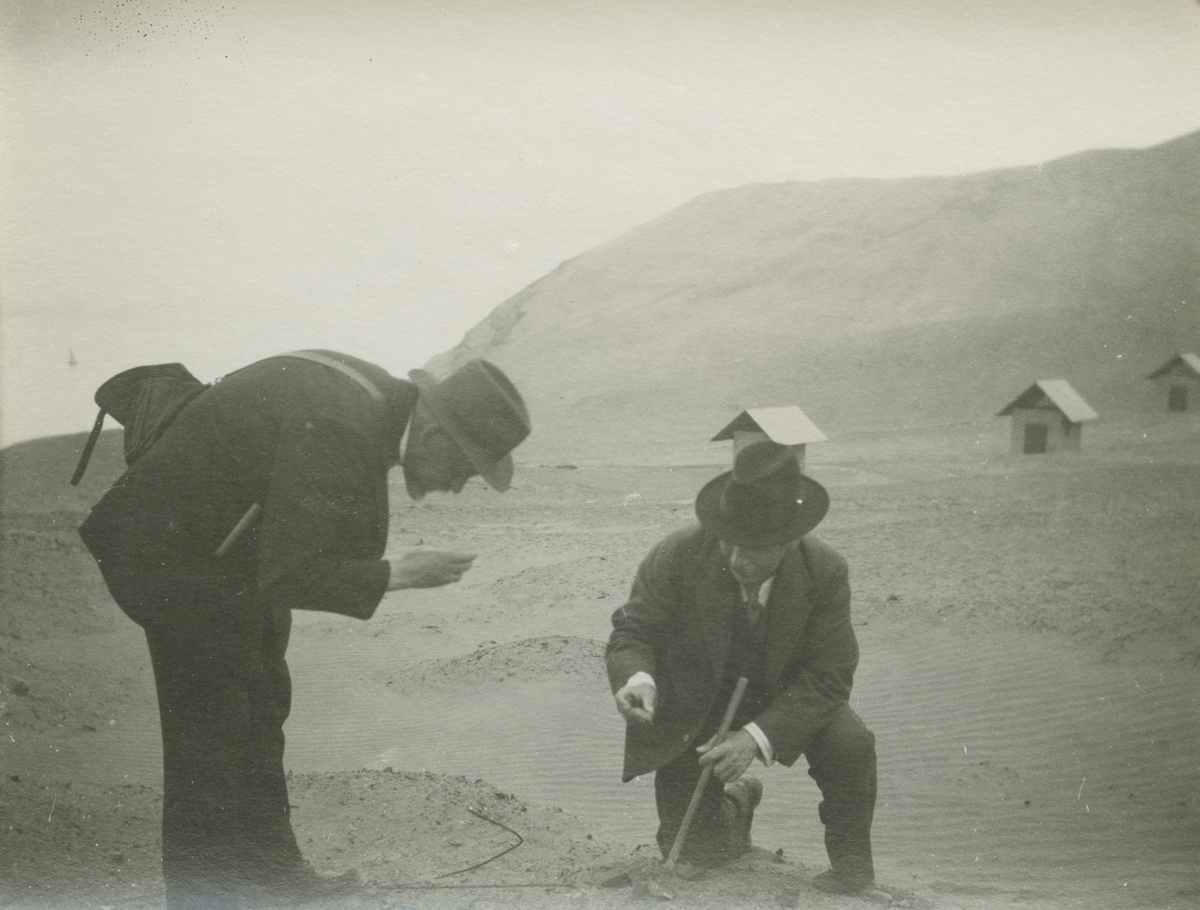 Fotografi från expedition till Peru 1920. Motiv av Otto Nordenskjöld och kollega på ön San Lorenzo. I bakgrunden syns berg och små stugor.