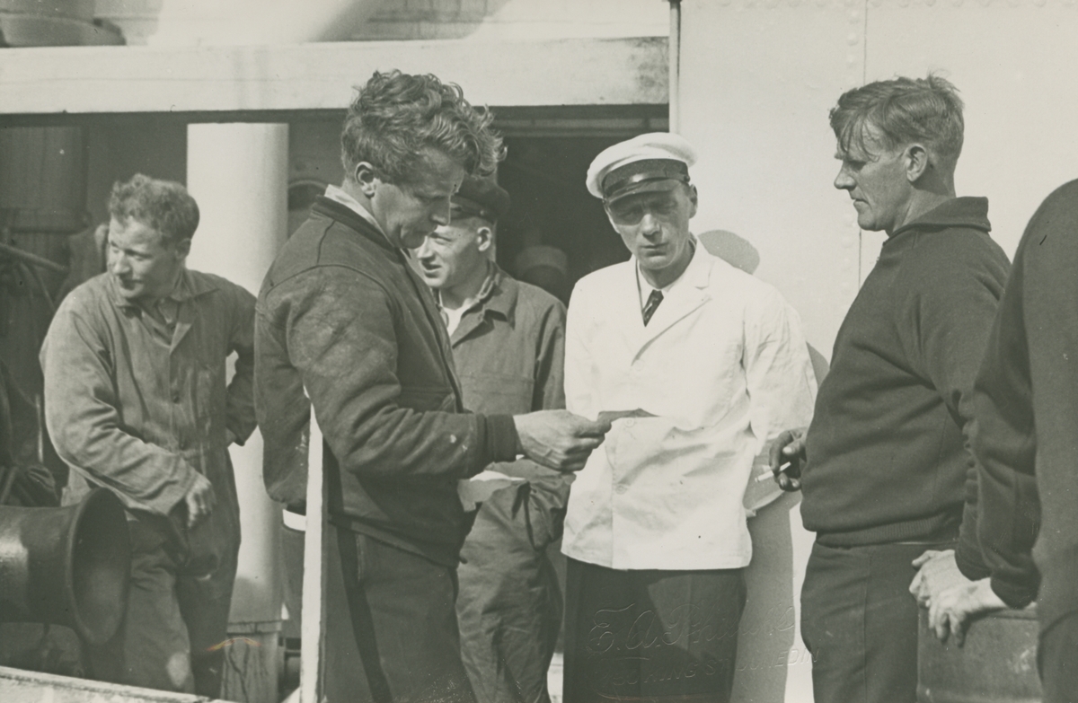 Fotografi från låda märkt Bernt Balchen. Balchen var norsk-amerikansk flygare, polarforskare och militär. Motiv av Balchen som läser brev ombord på båt.