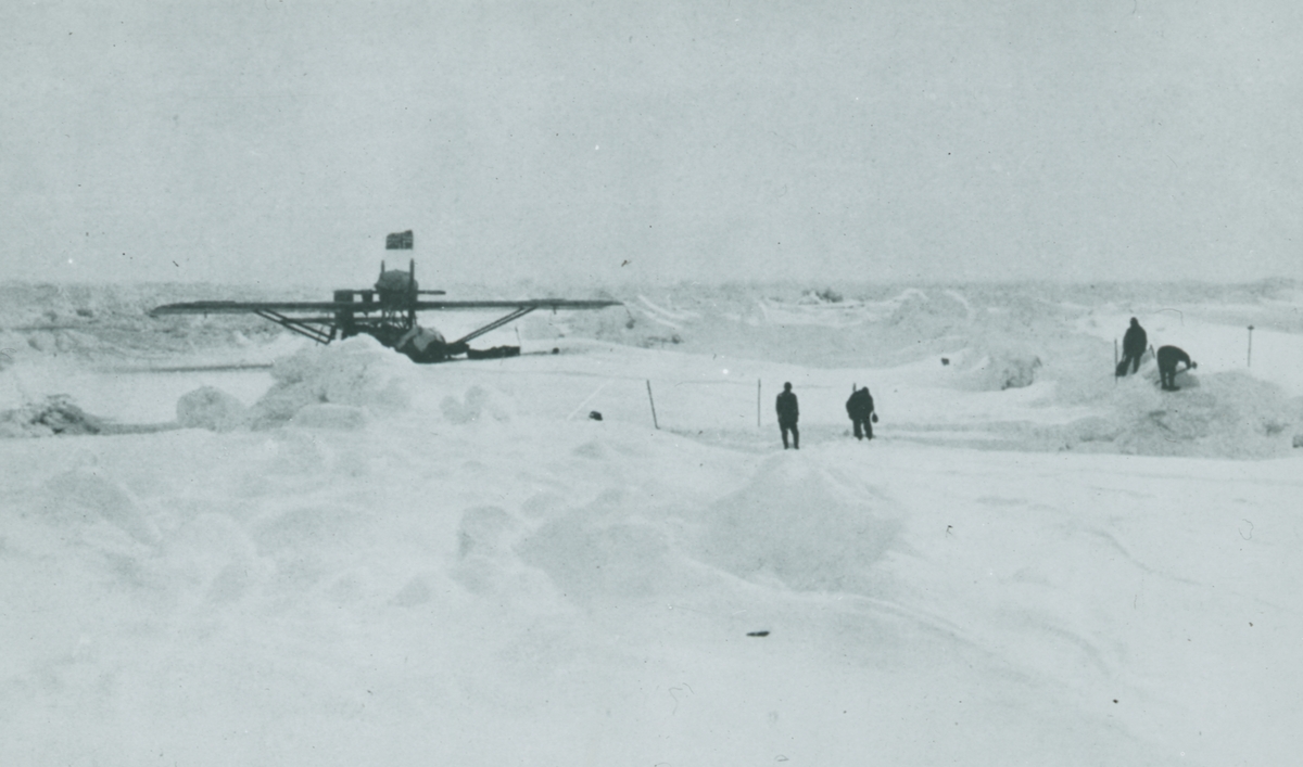 Glasnegativ med motiv av flygplan som landat i snö. På bilden syns även fyra personer i snön.