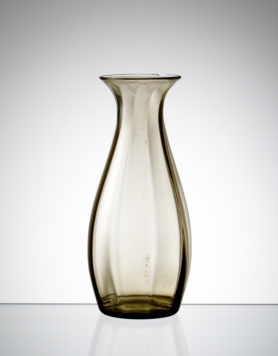 Formgiven av Edward Hald. Brun droppformad vas med utsvängd mynning. Utförd med stående optik.