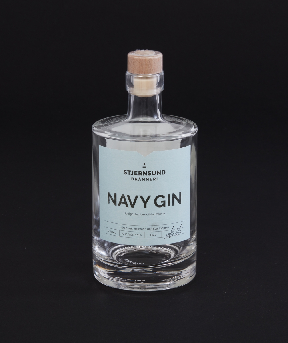 Flaska av klarglas. Etikett med text: "Navy Gin" samt mer text på etiketten och baksidan. Lock av trä och kork av plast. Tillverkad av Stjernsund Bränneri.
