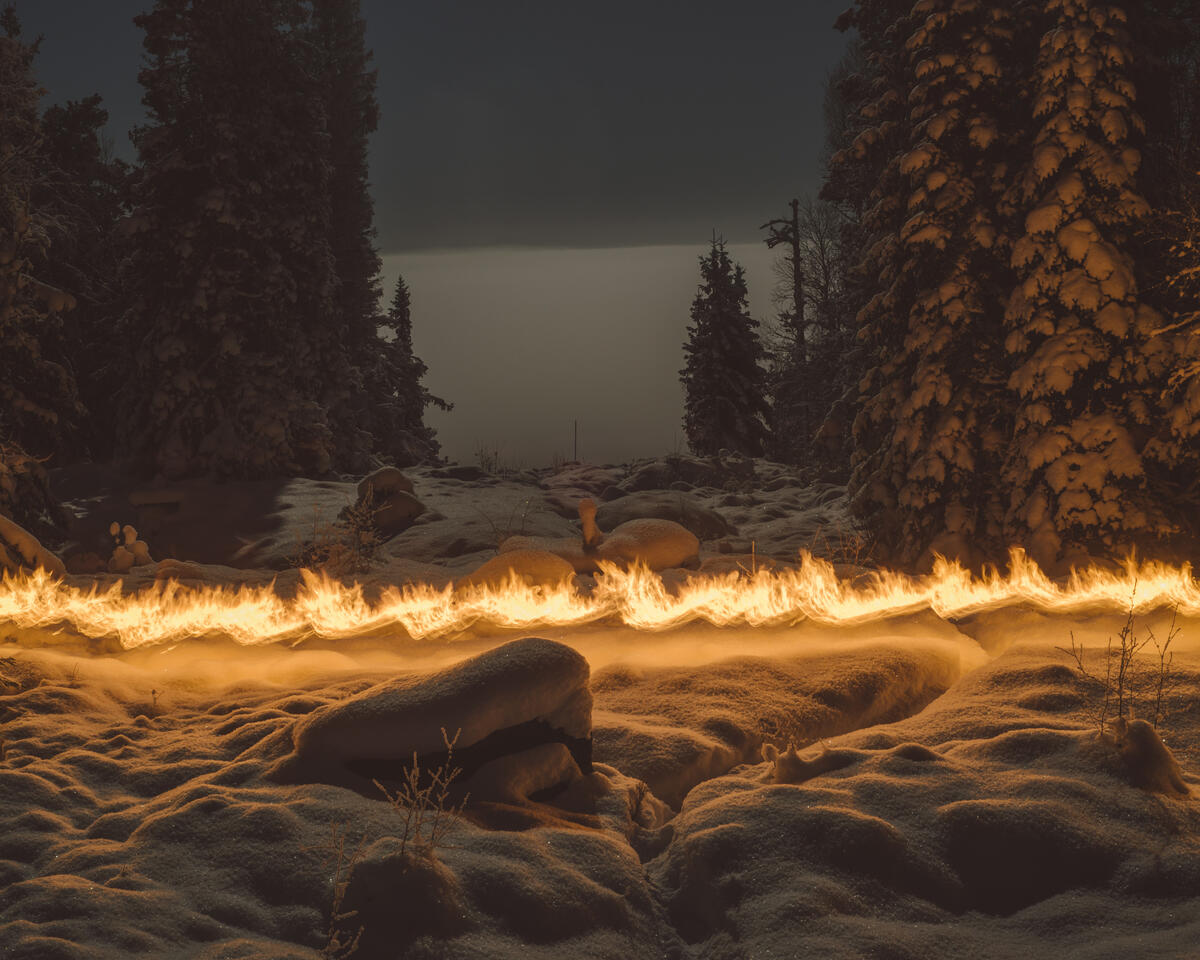 A dark winter landscape with spruce forest and a clearing in the middle of the forest. A fiery streak runs horizontally through the image. Photograph.