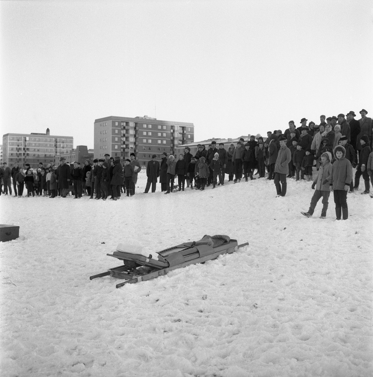 Oroliga linköpingsbor följer räddningsinsats i Stångån i höjd med stadsdelen Johannelund. Lyckligtvis kom inte räddningsbåren på bilden till användning. Under eftermiddagen framkom uppgiften att en pojke setts gående från ån med blöta kläder, och insatsen avbröts. Det hände den 14 januari 1961.
