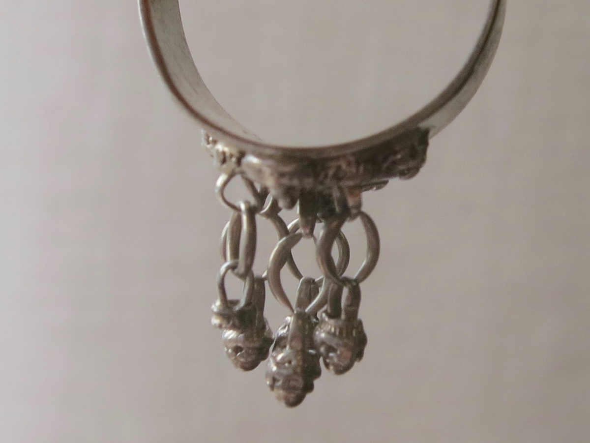 Silverring med fem små ringar med varsin liten kläpp. Troligen norskt ursprung, märkt 830.I.F. Användes som "en variant på fingran".