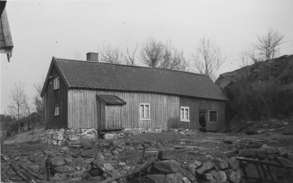 Gårdsbyggnad på stenig mark i Bröndome, Vallda. Ena gaveln ligger helt nära bergsknallen. Utbyggnaden är sannolikt ett dass.