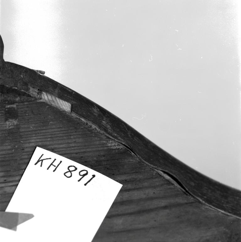 Del av soffrygg i nyrokokostil med fragment av tyg. Fanéren på överkanten skadad och saknas delvis