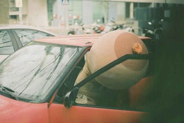 En rød bil og ut av bilen stikker det frem en tøyfigur av et kvinnebryst